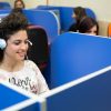 Operatrice che indossa delle cuffie e sorride mentre guarda il computer.