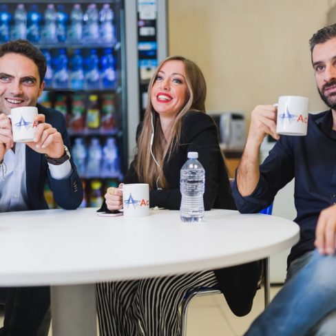 Gruppo di persone nell'area relax dell'azienda Accueil seduti ad un tavolino con delle tazze in mano.