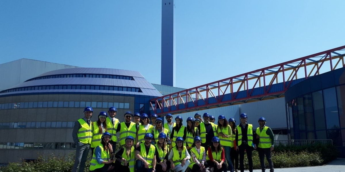Accueil-ConventionA2A_apr2018-03 Gruppo di persone che indossano giubbotti catarifrangenti e caschetti in visita al termo-utilizzatore A2A Ambiente di Brescia.
