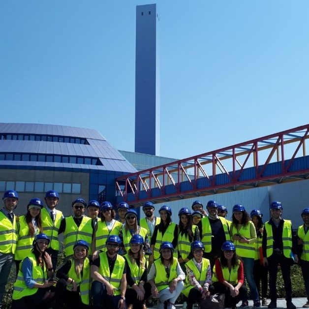 Accueil-ConventionA2A_apr2018-03 Gruppo di persone che indossano giubbotti catarifrangenti e caschetti in visita al termo-utilizzatore A2A Ambiente di Brescia.