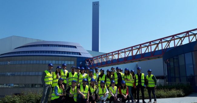 Gruppo di persone che indossano giubbotti catarifrangenti e caschetti in visita al termo-utilizzatore A2A Ambiente di Brescia.