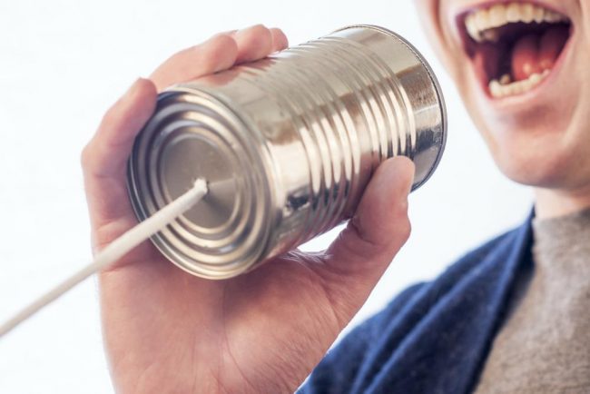 Bocca di uomo che parla dentro una scatola di latta alla quale è collegato un filo