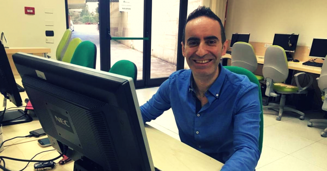 Uomo seduto davanti al computer che sorride