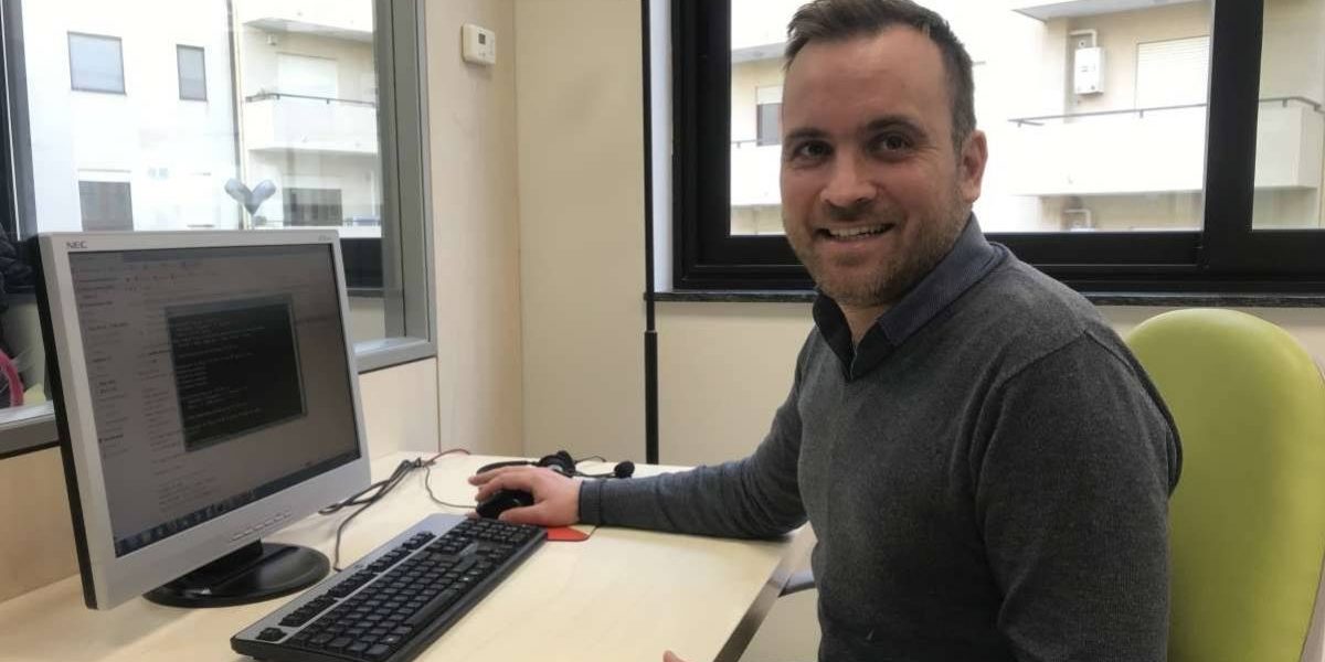 Antonino-Caridi Primo piano uomo che sorride seduto davanti al computer.