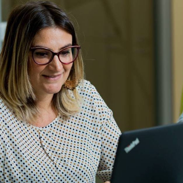 Marianna-Labozzetta Donna con occhiali seduta su una sedia verde che lavora al computer