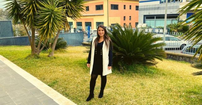 Ragazza in piedi in un giardino che sorride.