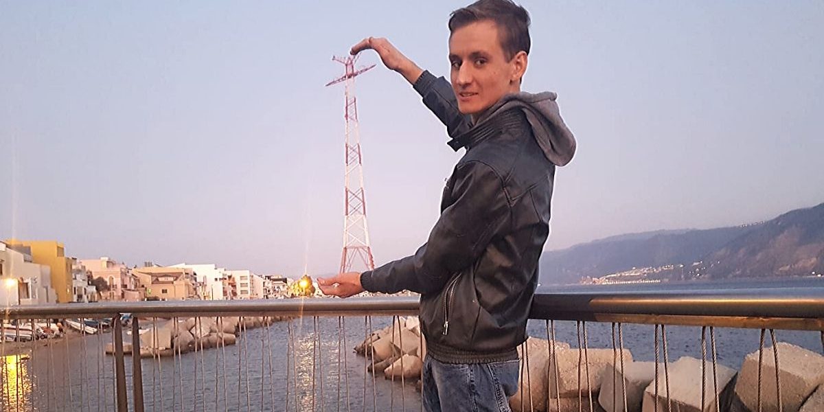 Giuseppe-Rando Ragazzo in piedi appoggiato al corrimano di un ponticello sul mare