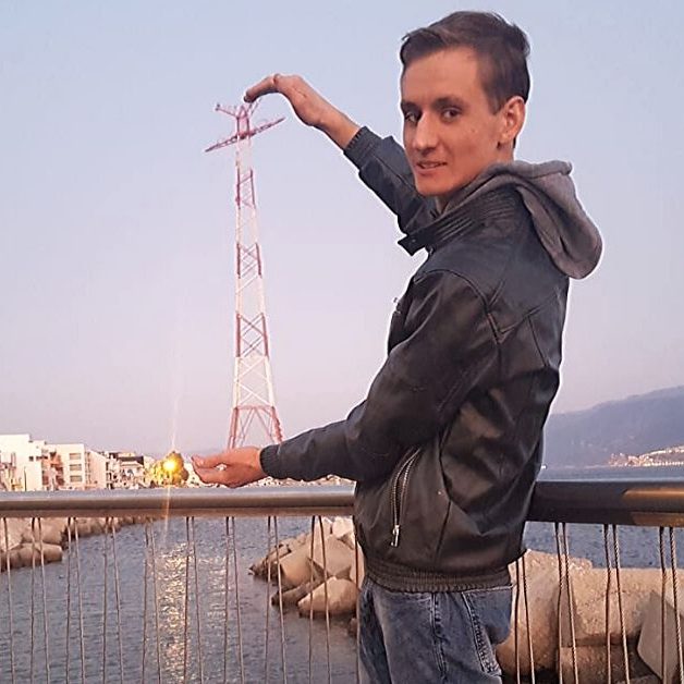 Giuseppe-Rando Ragazzo in piedi appoggiato al corrimano di un ponticello sul mare