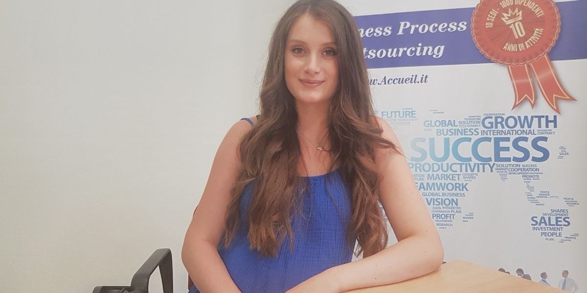 Mirjana-Avdiaj Ragazza seduta ad una scrivania che sorride