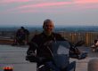 Foto al tramonto con un uomo in motocicletta