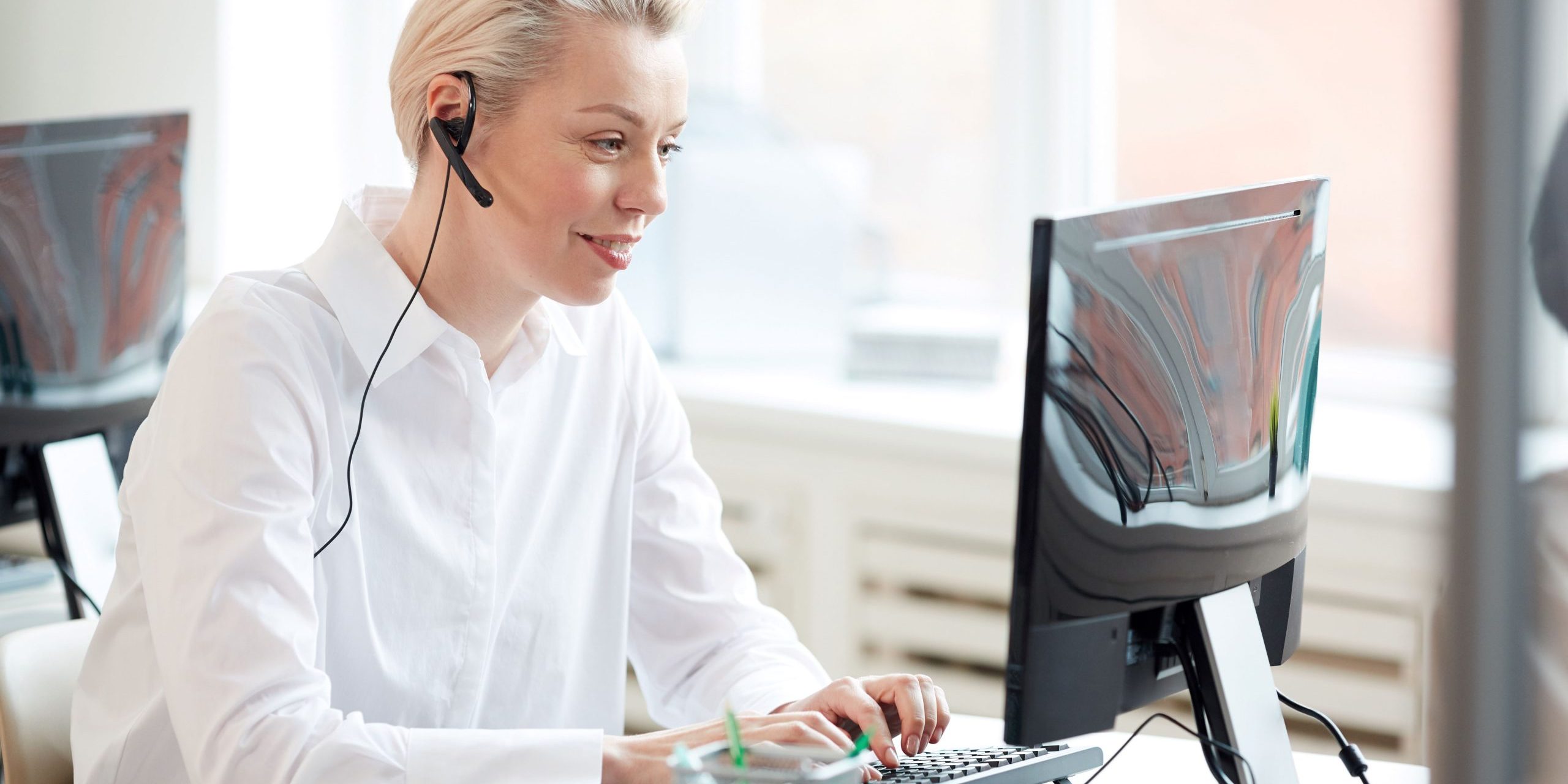 Call center inbound Donna che lavora al computer e indossa un auricolare.
