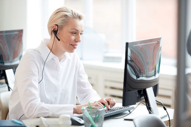 Donna che lavora al computer e indossa un auricolare.
