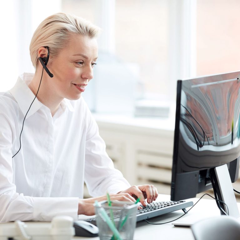 Call center inbound Donna che lavora al computer e indossa un auricolare.