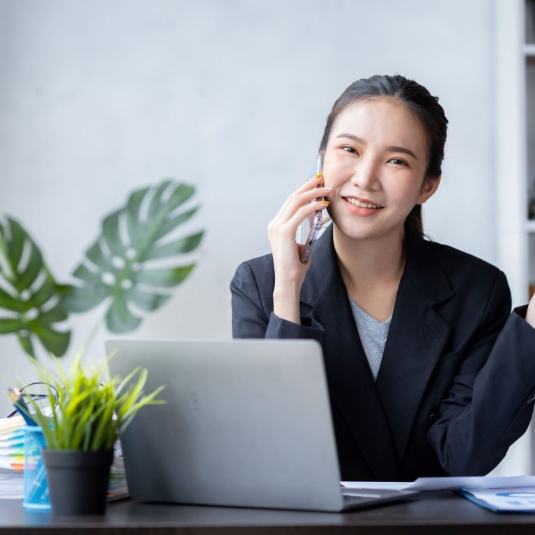 Teleselling Ragazza che parla al telefono davanti ad un computer portatile e tiene in mano una penna.